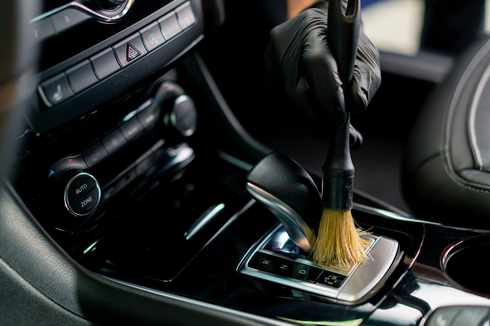 Car wash worker thoroughly cleaning the interior of a luxury car with a brush gear box,